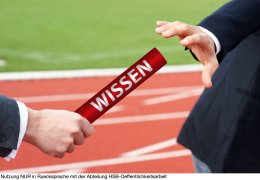 Business men passing baton in relay race in stadium with the German word Wissen means Knowledge