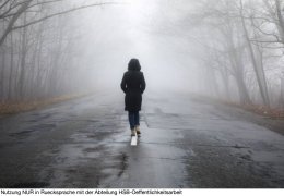 Einsame Frau lÅ uft im Nebel auf einer Strasse