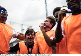 Players celebrating winning a medal on the soccer field - including a person with special needs