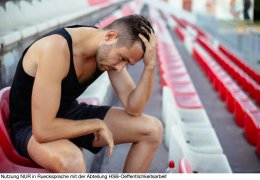 Depressed athlete man sitting head in hands on stadium seats