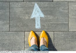 Female feet with arrow painted on the asphalt.