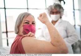 Woman being vaccinated and flexing biceps muscle - wearing face mask